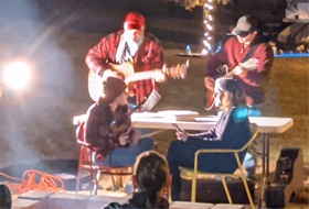 men playing guitar by a campfire at night