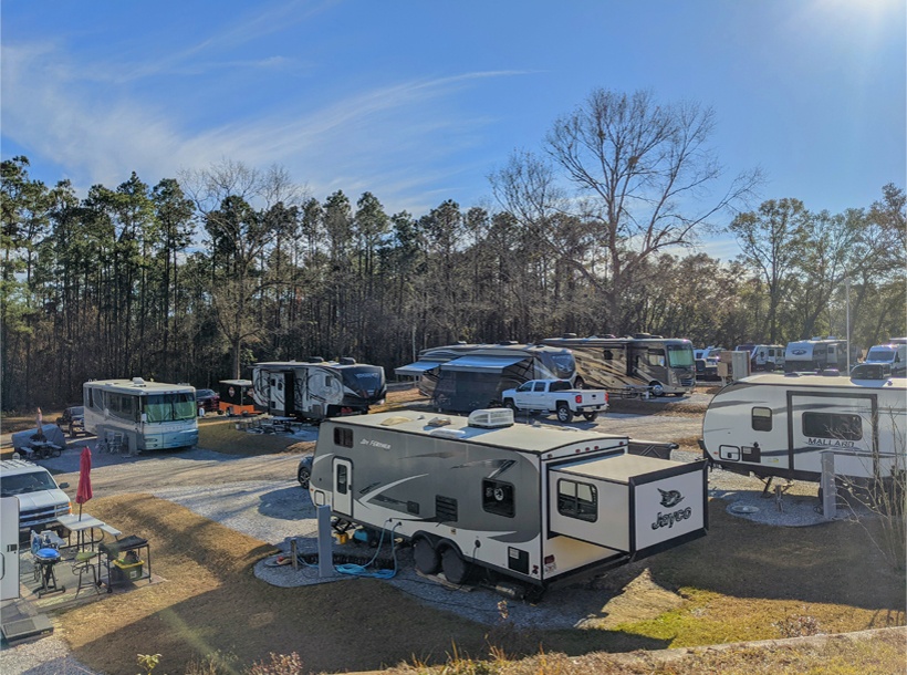 aerial view of RVs parked in clean, spacious camp sites with trees in the background