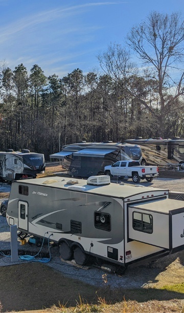 aerial view of RVs parked in clean, spacious camp sites with trees in the backgound